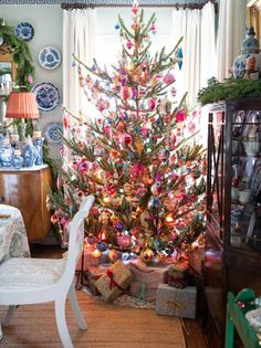 a decorated christmas tree in the corner of a dining room with plates on the table