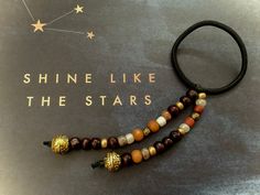 a necklace with beads on it and shine like the stars written in gold lettering above
