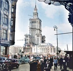 an old photo of people walking in front of a tall building with a clock tower