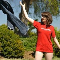 a woman in a red shirt is holding her jeans up to the sky with one hand