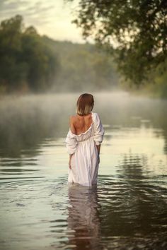 a woman is standing in the water with her back to the camera