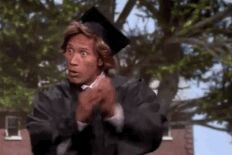 a man in a graduation cap and gown throwing a frisbee to someone else