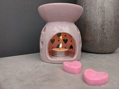 a small pink stove with two hearts on the counter next to it and a gray vase behind it