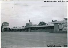 an old black and white photo of a street corner with buildings in the background, including a sign for william grocery - 1950