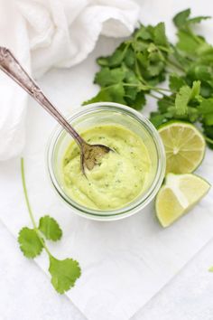 a spoon in a small jar filled with guacamole and cilantro