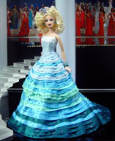a barbie doll dressed in a blue and green dress on display at a fashion show