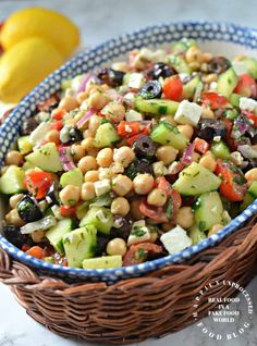a bowl filled with chickpeas and cucumber salad next to lemons