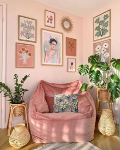a living room with pink walls and pictures on the wall, plants in vases