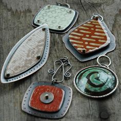 four different colored pendants sitting on top of a piece of wooden table next to each other