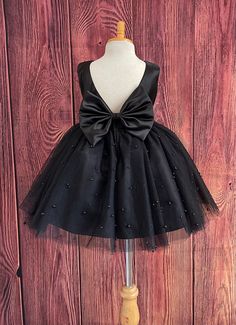 Little Darln Boutique  Our enchanting Knee Length flower girl dresses are sure to turn heads! This beautiful elegant sophisticated dress is handmade, the bodice consists of Black Bridal Satin with a sowed in sash at the waist, the back of the dress consists of an open V-back with a hidden zipper. The big bow is detachable. The skirt consists of 4 Black layers of tulle with the top layer consisting with sowed in pearl beads. The fifth layer is made of lining with crinoline for fullness.  This dress is perfect for any occasion!  Dress Is Pictured with a petticoat NOT INCLUDED https://www.etsy.com/listing/1316417982/white-knee-length-petticoat-wedding?click_key=41cb8b0ae4587efa582b0a433f3f5e0cde12aec0%3A1316417982&click_sum=af1df37b&ref=shop_home_active_1 Visit our store, more items to come! Flower Girl Dresses, Baby Dress, Black Flower Girl Dress, Black Flower Girl Dresses, Tulle Dress, White Flower Girl Dresses, Kids Dress, Girls Dresses