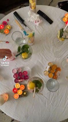 several candles are arranged on a round table with white linens and glass bowls filled with colorful candies
