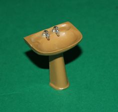 a yellow ceramic sink with two faucets on it's side and green background