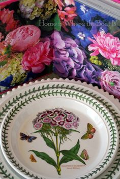 two plates with flowers painted on them sitting next to each other and a book in the background
