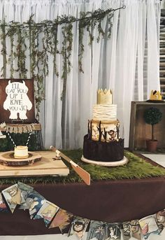a table topped with cakes and desserts on top of a wooden tray covered in green grass