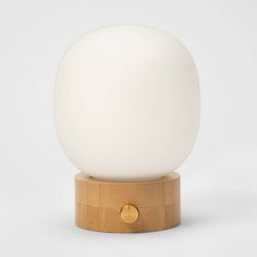 a white ball sitting on top of a wooden stand next to a light brown base