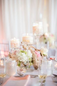 the table is set with candles, flowers and wine glasses for an elegant wedding reception