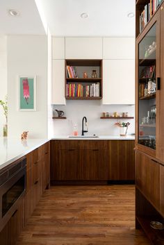 a kitchen with wooden cabinets and white counter tops, along with bookshelves on the wall