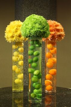 three vases filled with different types of flowers and fruits in them on a table