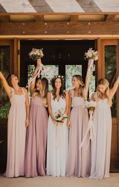 a group of women standing next to each other in front of a door holding bouquets