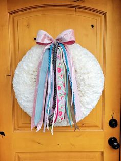 a wreath with ribbons hanging on the front door to give as a decoration for someone's home