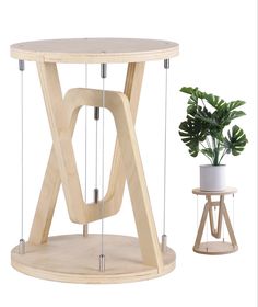 a wooden table with two small stools next to it and a potted plant