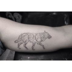 a black and white photo of a bear tattoo on the right arm, with circles in it