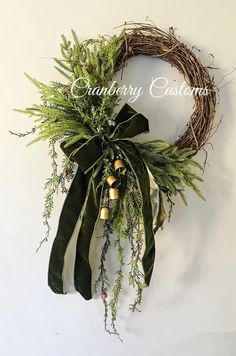 a wreath with greenery and bells hanging on the wall