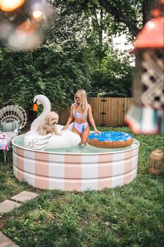 a woman is sitting in a pool with a dog and a stuffed animal on it