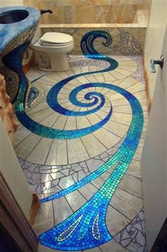 a bathroom with blue and white mosaic tiles on the floor, toilet and sink area