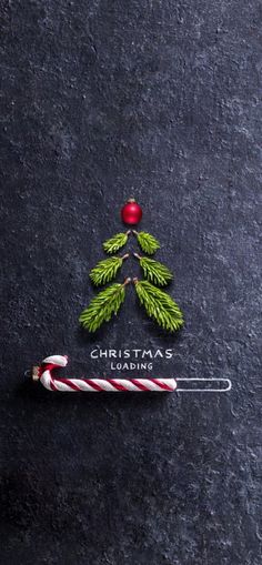 a candy cane sitting on top of a black surface next to a christmas tree ornament