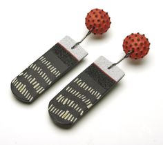 two red and black earrings with polka dots on them, sitting next to each other