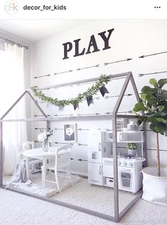 a play room with white furniture and plants on the wall, including a doll house