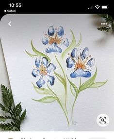 watercolor painting of blue flowers on white paper with green leaves next to it and plant