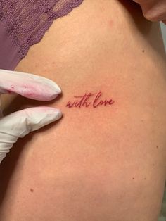 a woman's stomach with the word love written on it and a glove holding up her arm