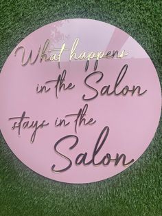 a pink sign that says what happens in the salon days in the salon on grass