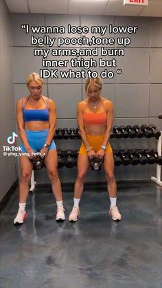 two women in sports bras and shorts sitting on a bench with dumbbells