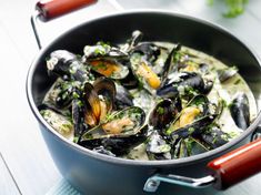 a pan filled with mussels and sauce on top of a table