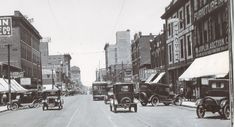an old black and white photo of cars driving down the street