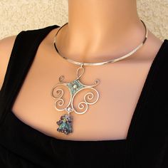 a woman wearing a silver necklace with a blue crystal pendant on it's neck