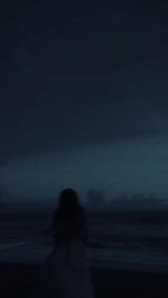 a person standing on the beach at night