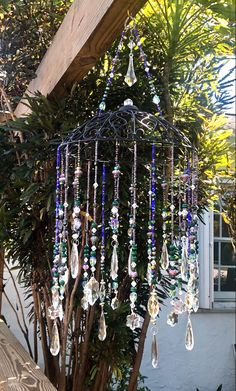 a wind chime hanging from a tree in front of a building with lots of glass beads