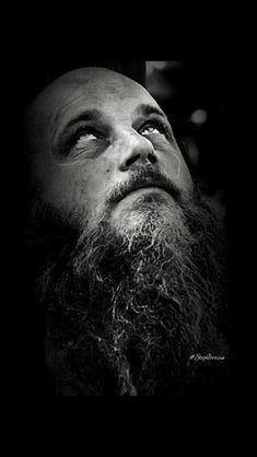 a black and white photo of a man with a beard looking up at the sky