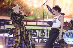 two women are performing on stage with microphones in their hands and one is wearing plaid pants