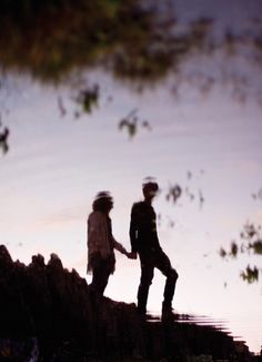 two people standing on top of a hill holding hands