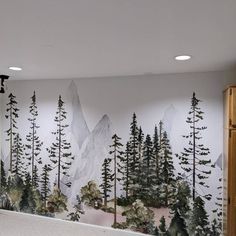 a large mural in the corner of a room with trees and mountains painted on it