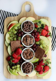 an assortment of fruit and chocolates on a wooden platter with black and white stripes