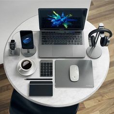 a laptop computer sitting on top of a white table next to a mouse and headphones