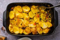 a casserole dish with potatoes and vegetables in it on a plate next to a fork