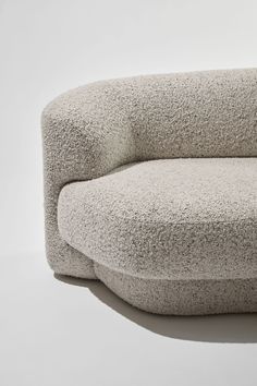 an oval shaped couch made out of grey wool with a white back and seat cushion