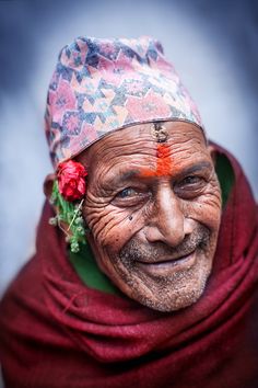 an old man with a flower in his hair and wearing a red scarf around his neck